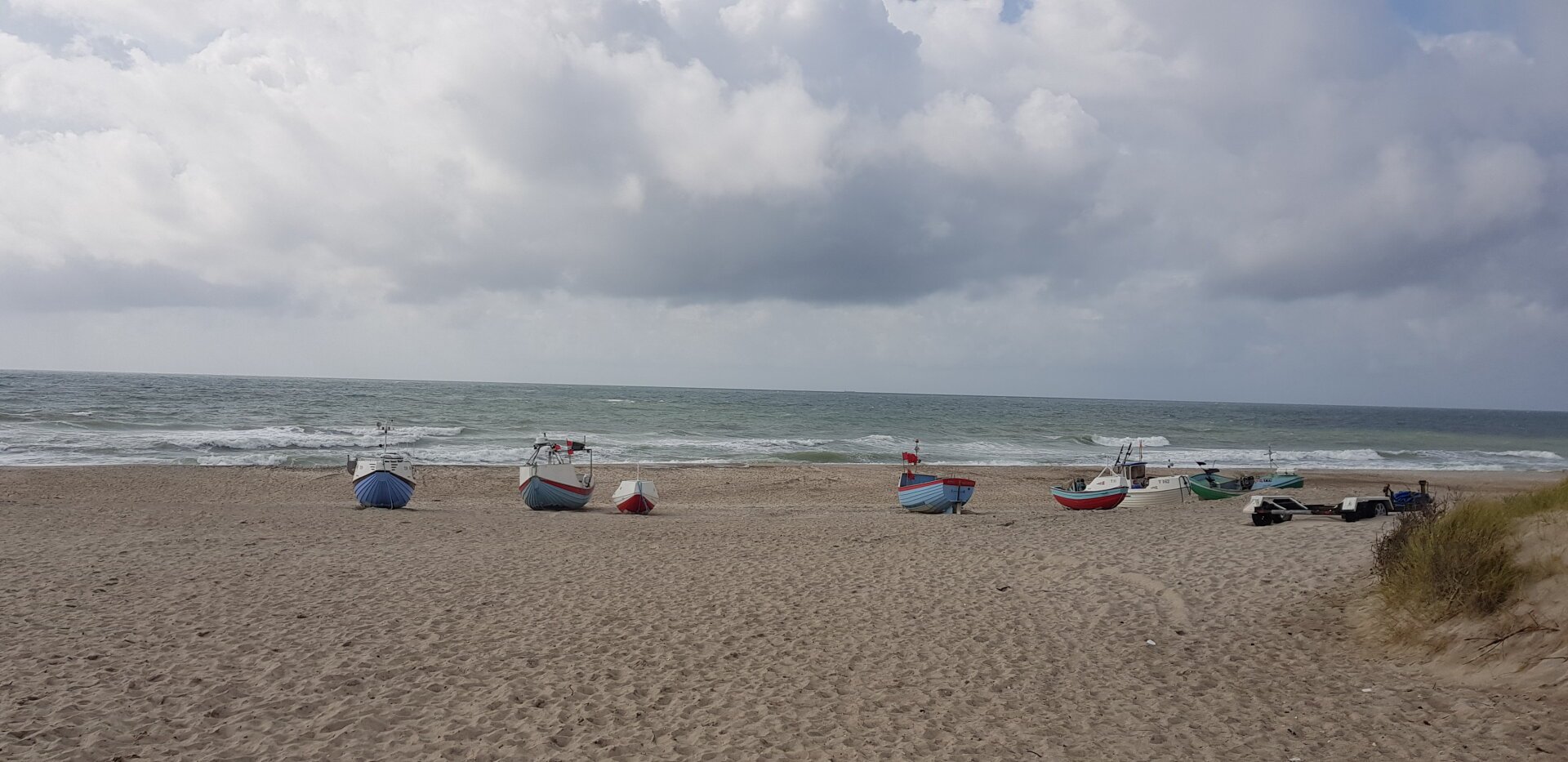 Sandy beach with small fishing boats. The boats have been drawn up on the beach.